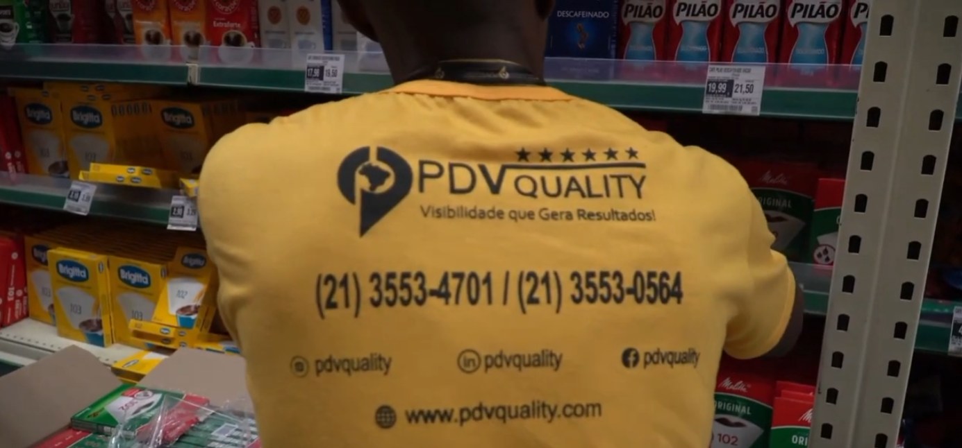 Promotor da PDV Quality com a camisa amarela da marca abastecendo a gôndola